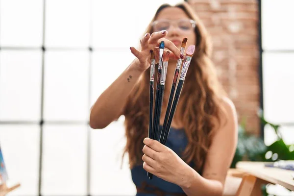 Young Beautiful Hispanic Woman Artist Holding Paintbrushes Art Studio — Stock fotografie