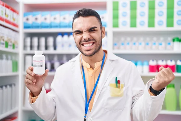 Jovem Hispânico Trabalhando Farmácia Farmácia Farmácia Segurando Pílulas Gritando Orgulhoso — Fotografia de Stock