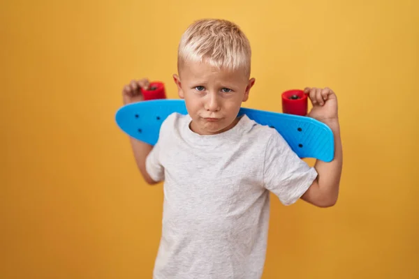 スケートを保持している小さな白人の少年は落ち込んでおり 苦痛を心配し 怒って恐れて泣いています 悲しい表情 — ストック写真