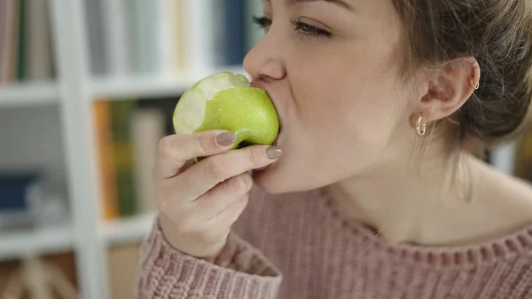 在图书馆大学吃青苹果的年轻貌美女人 — 图库照片