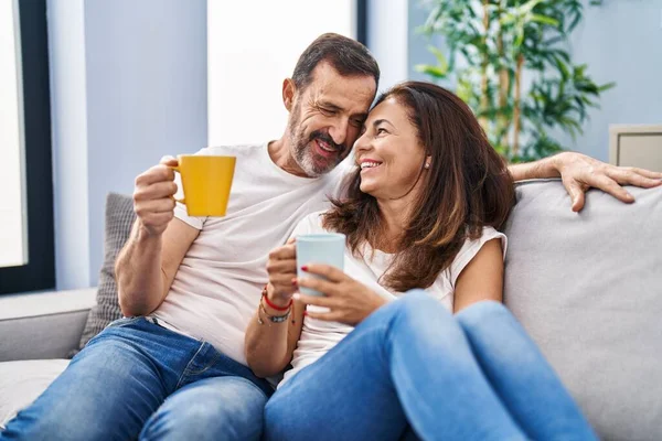 中年男性と女性カップル飲むコーヒー座っています上のソファにホーム — ストック写真