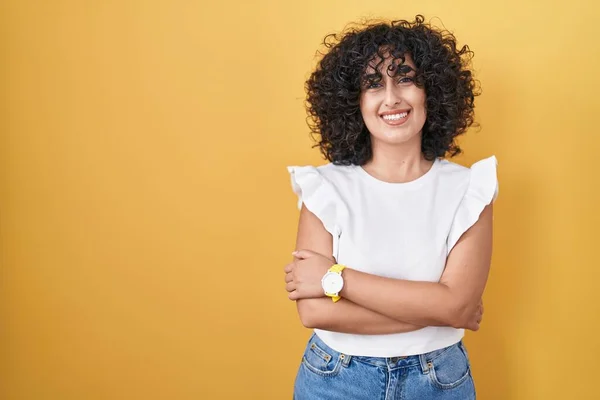 年轻的中东女人站在黄色的背景上开心地微笑着 交叉着双臂看着摄像机 积极的人 — 图库照片