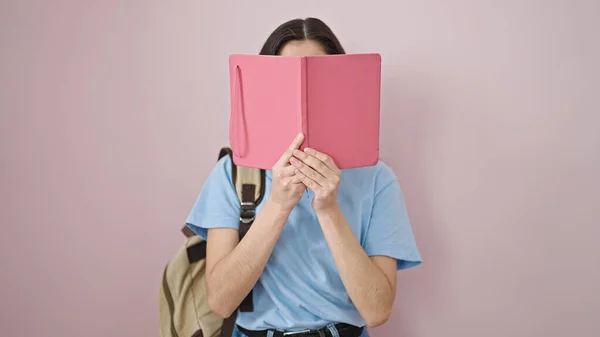 Молодая Красивая Латиноамериканка Покрывающая Лицо Книгой Изолированном Розовом Фоне — стоковое фото
