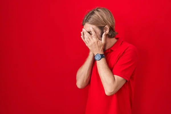 一个白种人 留着胡子 站在红色的背景上 脸上挂着悲伤的表情 一边哭一边用手捂住脸 抑郁症的概念 — 图库照片