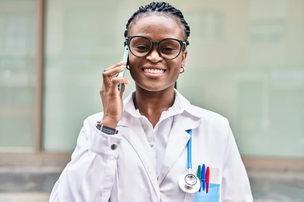 Mujer Afroamericana Doctora Sonriendo Confiada Hablando Teléfono Inteligente Hospital —  Fotos de Stock