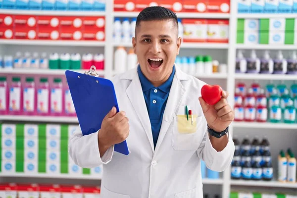 Νεαρός Ισπανός Που Εργάζεται Στο Φαρμακείο Κρατώντας Την Καρδιά Χαμογελώντας — Φωτογραφία Αρχείου