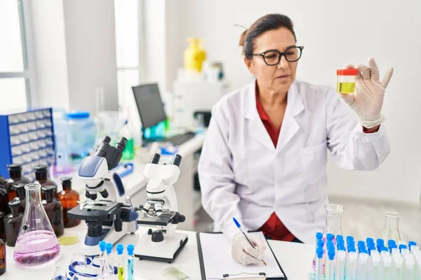 Middle Age Hispanic Woman Wearing Scientist Uniform Analysing Urine Test — Stockfoto