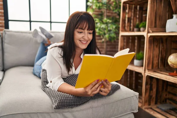 Young Beautiful Hispanic Woman Reading Book Lying Sofa Home — Stock Photo, Image
