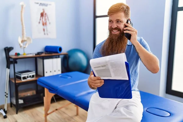 Junger Rothaariger Mann Physiotherapeutenuniform Spricht Auf Dem Smartphone Der Physiotherapie — Stockfoto
