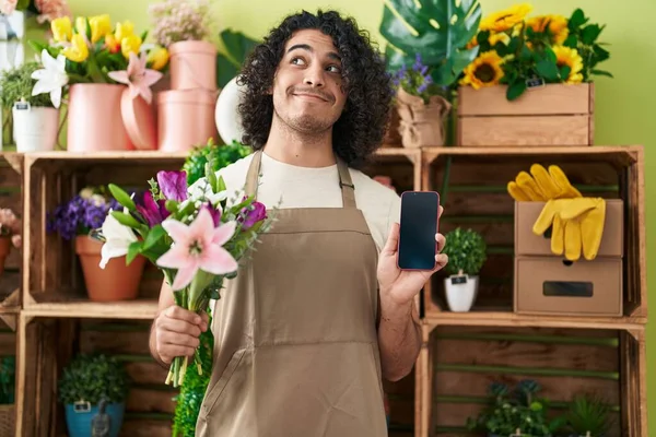 Hispánec Kudrnatými Vlasy Pracující Květinářství Zobrazující Obrazovku Smartphonu Usmívající Stranou — Stock fotografie