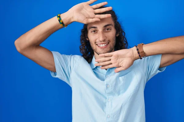 Mladý Hispánec Který Stojí Nad Modrým Pozadím Vesele Usmívá Vykukuje — Stock fotografie