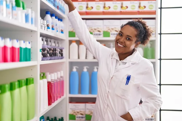 Afro Amerikaanse Vrouw Apotheker Glimlachend Zelfverzekerd Holding Product Van Rekken — Stockfoto