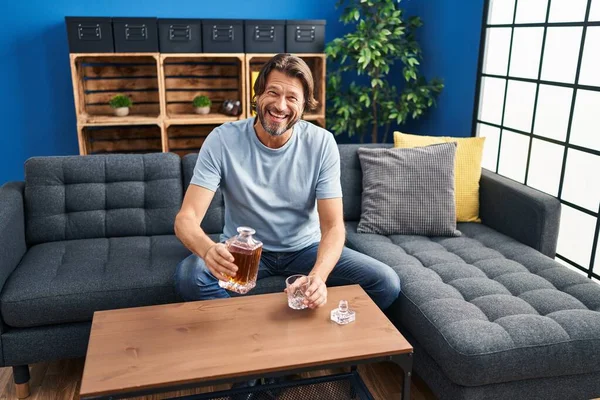 Middelbare Leeftijd Man Met Glas Fles Whisky Zittend Bank Thuis — Stockfoto