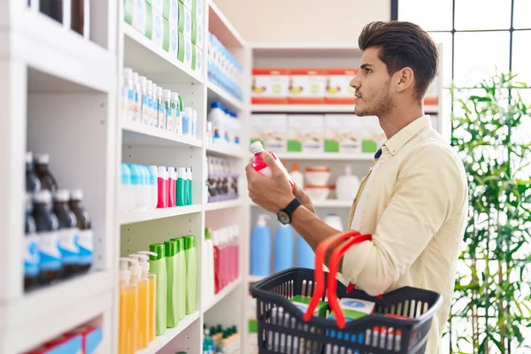 Junger Hispanischer Mann Mit Medikamentenflasche Und Einkaufskorb Apotheke — Stockfoto