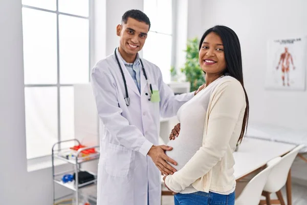 年轻的拉丁夫妇医生和病人在诊所触摸腹部 — 图库照片