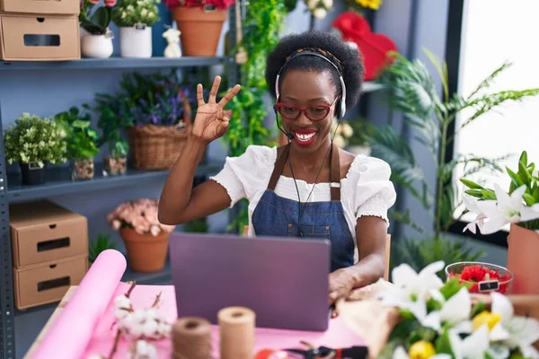 非洲妇女 在花店工作 做视频通话 用手指做手势 微笑友善地摆姿势 是极好的象征 — 图库照片