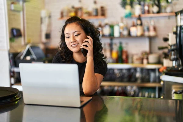 Young Chinese Woman Waitress Using Laptop Talking Smartphone Restaurant — Zdjęcie stockowe