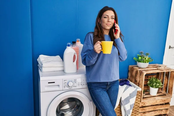 Jonge Spaanse Vrouw Praten Smartphone Wachten Wasmachine Wasruimte — Stockfoto