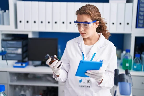 Young Beautiful Hispanic Woman Scientist Using Touchpad Holding Bottle Laboratory —  Fotos de Stock