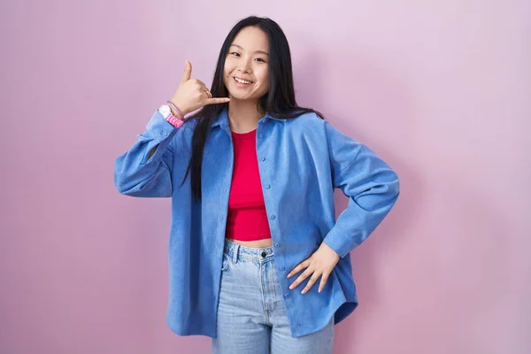 Young Asian Woman Standing Pink Background Smiling Doing Phone Gesture — Zdjęcie stockowe