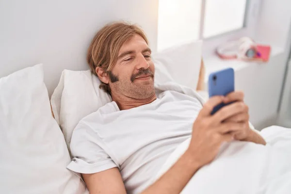 Fiatal Szőke Férfi Használ Smartphone Feküdt Ágyon Hálószobában — Stock Fotó