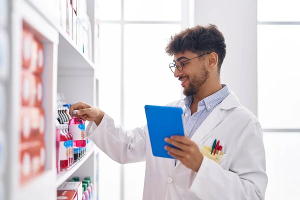 stock image Young arab man pharmacist using touchpad holding medicine bottle at pharmacy