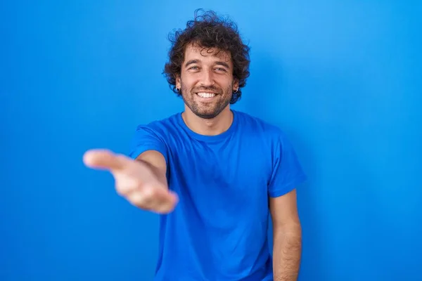 Spaanse Jongeman Staat Blauwe Achtergrond Glimlachend Vrolijk Aanbieden Palm Hand — Stockfoto