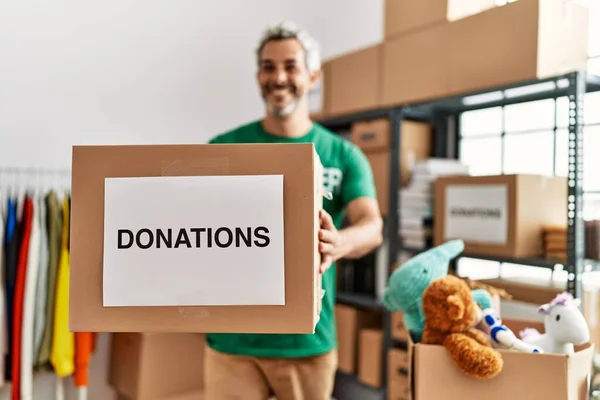 Hombre Pelo Gris Mediana Edad Voluntario Sonriendo Confiado Sosteniendo Donaciones —  Fotos de Stock
