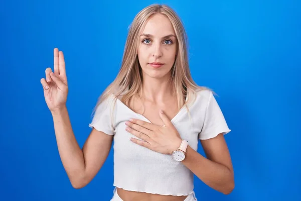 Young Caucasian Woman Standing Blue Background Smiling Swearing Hand Chest — Stock Photo, Image