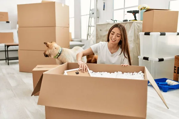 Young Hispanic Woman Unboxing Package Sitting Floor Dog New Home — ストック写真