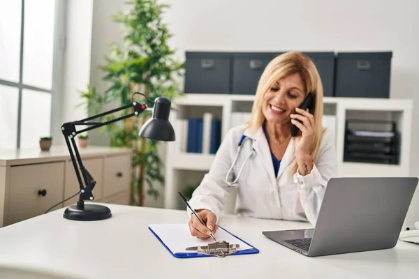 Middle Age Blonde Woman Wearing Doctor Uniform Talking Smartphone Clinic — Stock Photo, Image