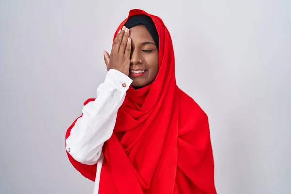 手で一つの目を覆う伝統的なイスラム教のヒジャーブスカーフを身に着けている若いアラブ女性 顔に自信を持って笑顔と驚きの感情 — ストック写真