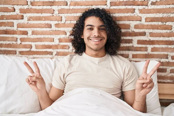 Genç Latin Adam Yatakta Oturmuş Zafer Jesti Yapıyor — Stok fotoğraf