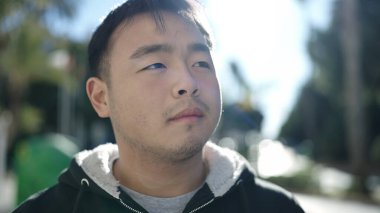 Young chinese man looking to the side with serious expression at street
