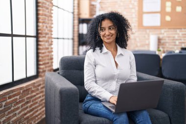 Ofiste çalışan genç İspanyol iş kadını laptopu kullanıyor.