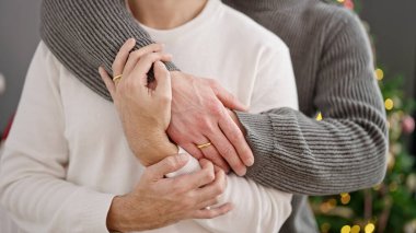 İki erkek, evde alyans göstererek Noel 'i kutluyor.