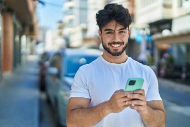 Sokakta akıllı telefon kullanan, kendine güvenen genç bir İspanyol.