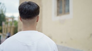 Genç İspanyol adam caddede geri geri duruyor.