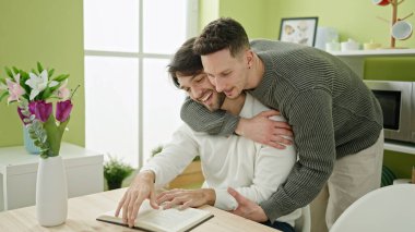 Two men reading book sitting on table at dinning room clipart