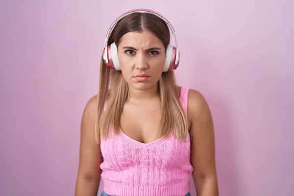 Mujer Rubia Joven Escuchando Música Usando Auriculares Escépticos Nerviosos Frunciendo —  Fotos de Stock