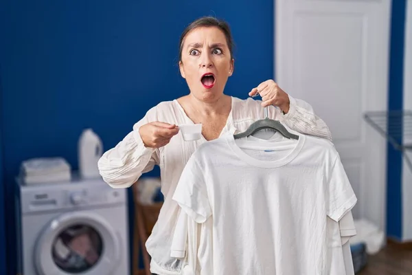 Middle Age Hispanic Woman Holding Shirt Hanger Detergent Powder Shock — Stock Photo, Image