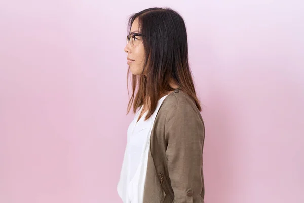 stock image Middle age chinese woman wearing glasses over pink background looking to side, relax profile pose with natural face with confident smile. 