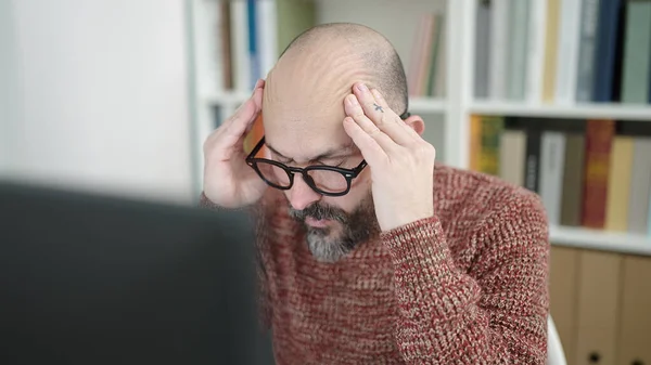 Young bald man student using computer stressed at university classroom ...
