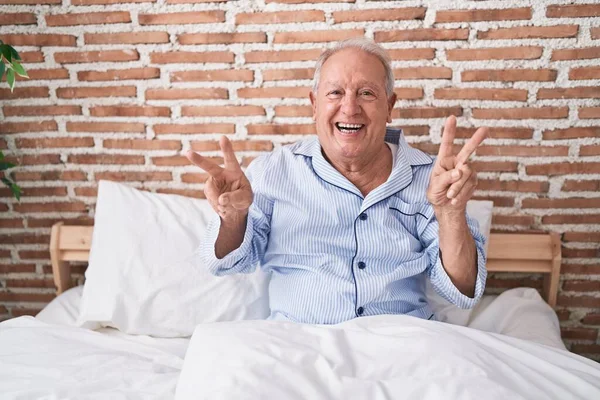 Medelålders Gråhårig Man Gör Segergest Sittandes Sängen Sovrummet — Stockfoto