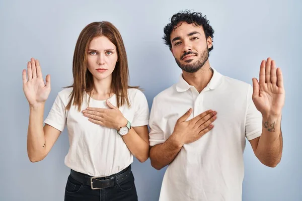 Young Couple Wearing Casual Clothes Standing Together Swearing Hand Chest — Stock Photo, Image