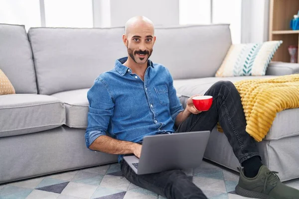 若いですヒスパニック系男を使用してノートパソコンのコーヒーを飲む自宅で — ストック写真