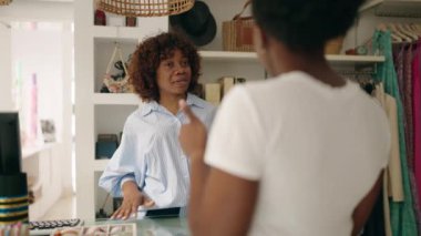 African american women shop assistant and customer speaking at clothing store