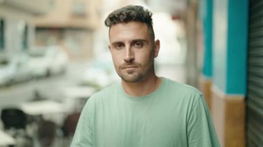 Genç İspanyol adam sokakta el hareketlerini durduruyor.