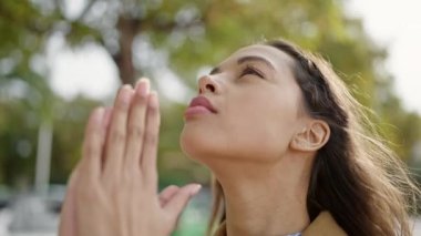 Parkta gözleri kapalı dua eden genç, güzel İspanyol kadın.