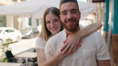 Kadın ve erkek gülümsüyor. Kendilerine güveniyorlar. Sokakta sarılıyorlar.
